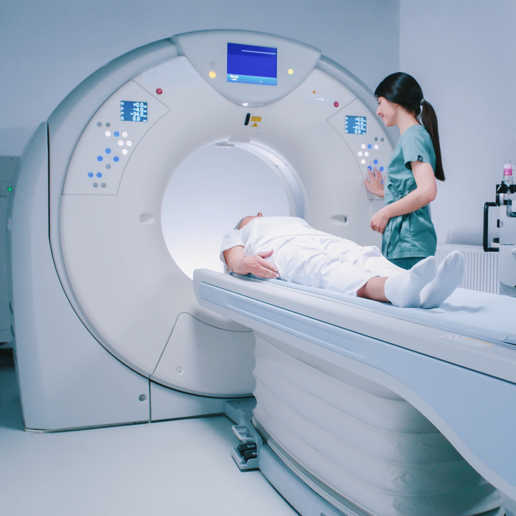 Patient is getting recommendations from doctor before MRI procedure. Woman is lying down at CT scanner bed. Female is moving into MRI scanner capsule. Female doctor is conducting tomography examining.